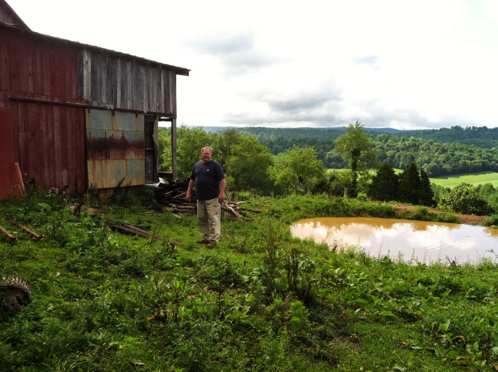 Photo of Eric Price and the c. 1905 barn on the farm where he grew up.