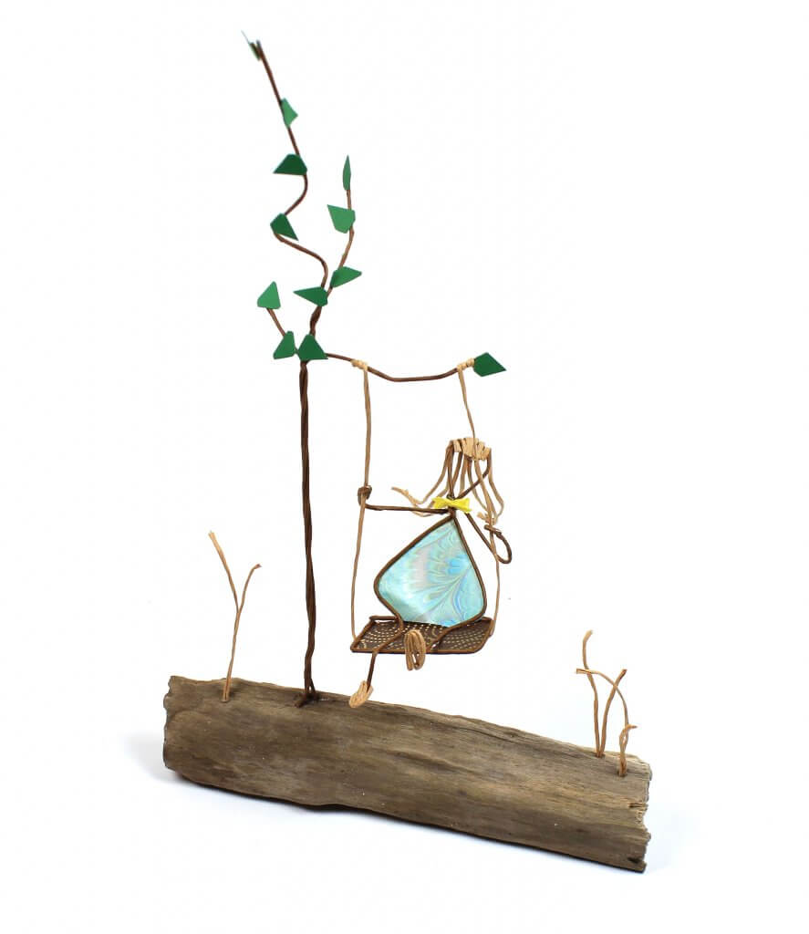 Image of Girl on a Tree Swing, a sculpture in wire and cut paper on driftwood.
